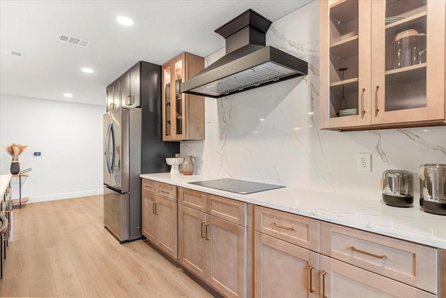 kitchen with visible vents, freestanding refrigerator, black electric cooktop, ventilation hood, and light wood-type flooring