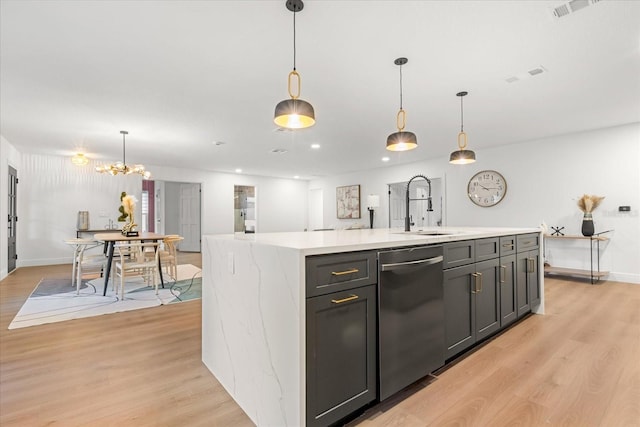 kitchen featuring light countertops, dishwasher, light wood finished floors, and a sink