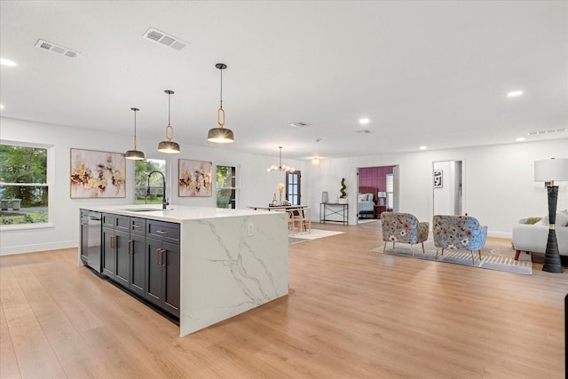 kitchen featuring dishwasher, light wood-style floors, open floor plan, and a sink