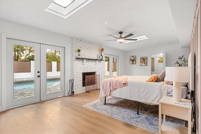 bedroom with a skylight, french doors, light wood-style floors, a ceiling fan, and access to outside