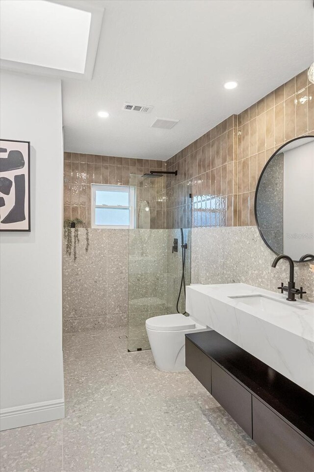 full bath featuring a walk in shower, toilet, visible vents, vanity, and tile walls