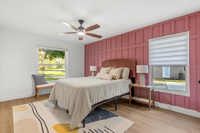 bedroom with light wood finished floors, multiple windows, and baseboards