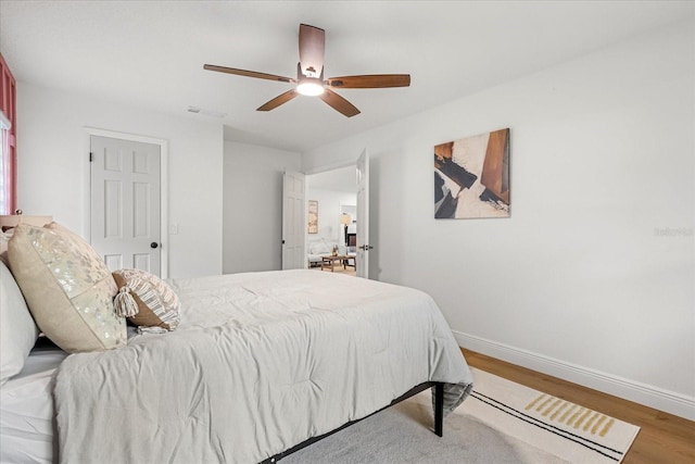 bedroom with visible vents, light wood-type flooring, a ceiling fan, and baseboards