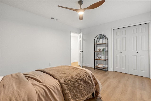 bedroom with light wood finished floors, a closet, visible vents, ceiling fan, and baseboards