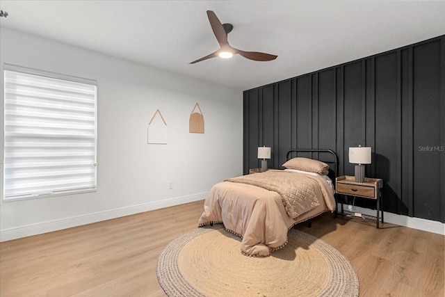 bedroom with a ceiling fan, baseboards, and light wood finished floors