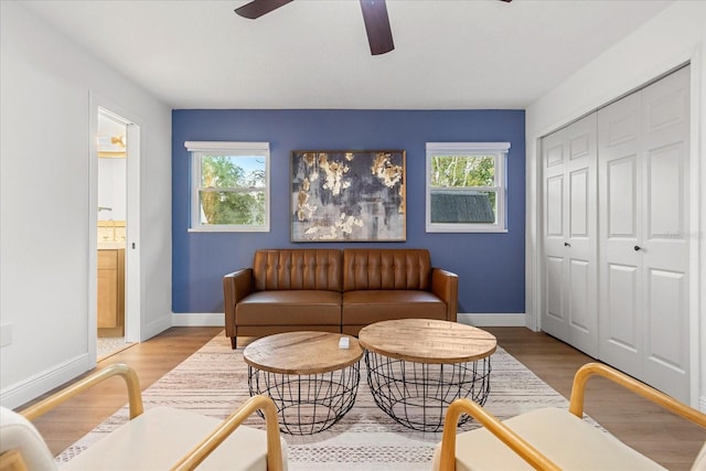 sitting room with a ceiling fan, a wealth of natural light, baseboards, and wood finished floors