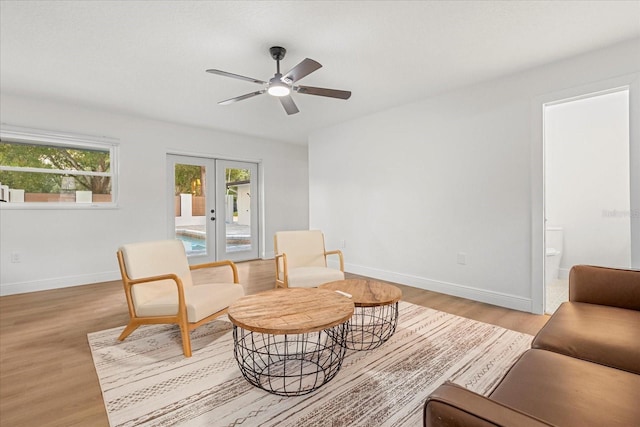 sitting room with light wood-style flooring, baseboards, a ceiling fan, and french doors