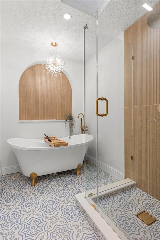 full bath featuring tile patterned flooring, a freestanding bath, a shower stall, and a textured ceiling