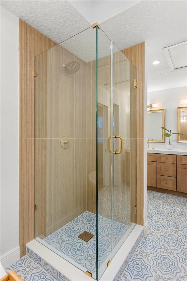 full bathroom with tile patterned flooring, a shower stall, vanity, and a textured ceiling