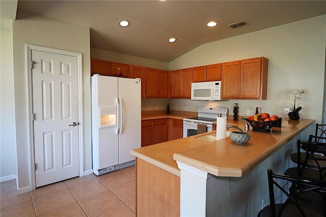 kitchen with lofted ceiling, white appliances, a kitchen bar, light tile patterned flooring, and kitchen peninsula