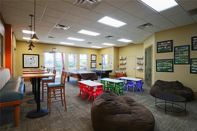 game room with dark colored carpet and a paneled ceiling