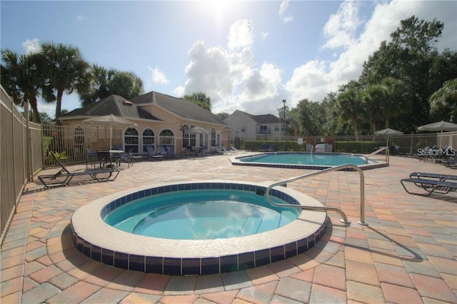 view of swimming pool featuring a hot tub and a patio