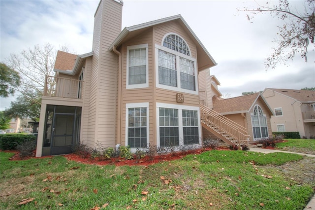 view of side of home with a balcony and a lawn