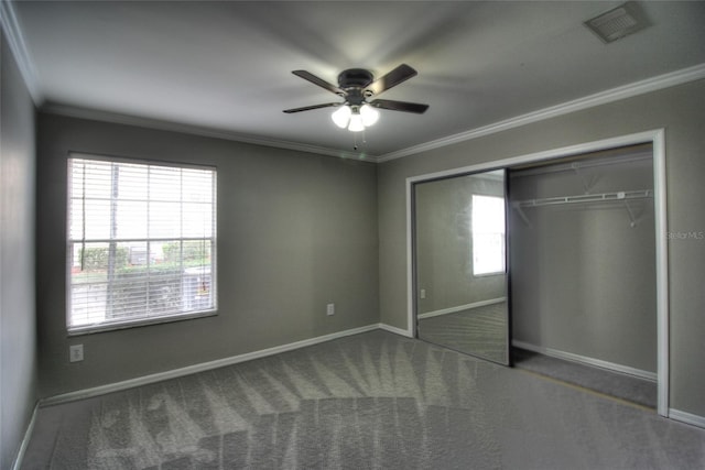 unfurnished bedroom with crown molding, ceiling fan, dark carpet, and a closet