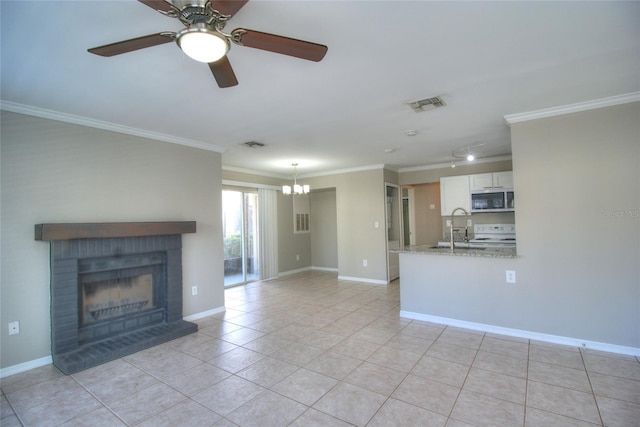 unfurnished living room featuring crown molding, a sink, light tile patterned flooring, a chandelier, and a brick fireplace