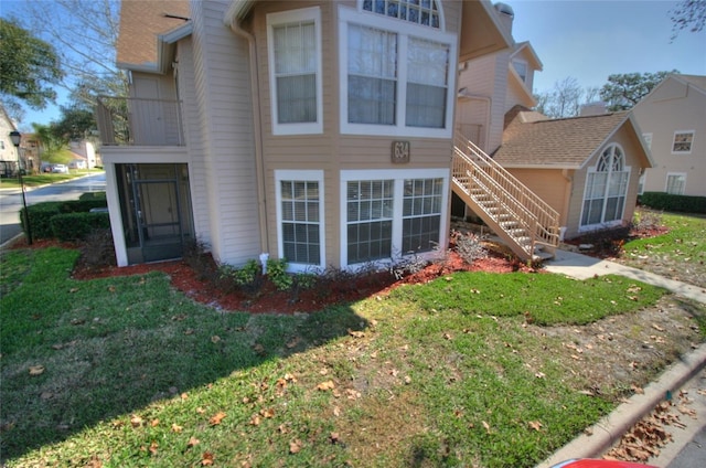 view of front of property featuring stairs, a front yard, and a sunroom