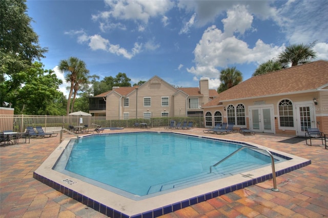 community pool with french doors, fence, and a patio