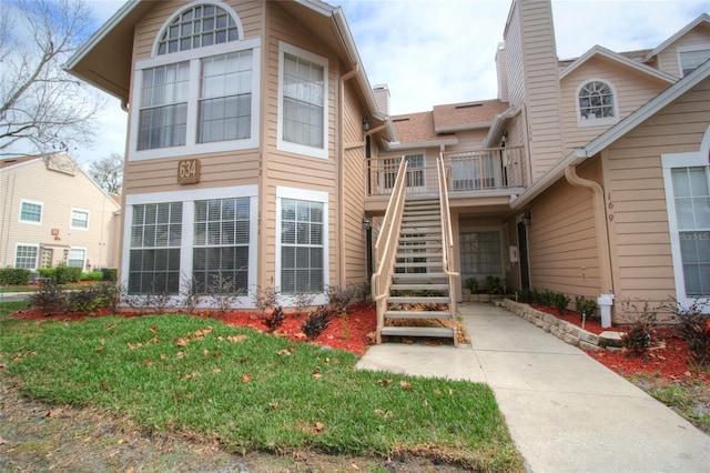 view of front of property featuring stairs, a front lawn, and a chimney
