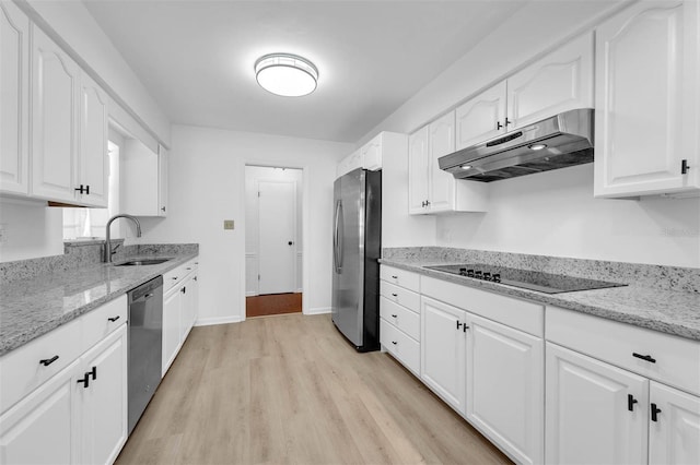 kitchen with under cabinet range hood, white cabinetry, appliances with stainless steel finishes, and a sink