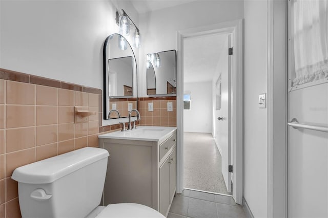 bathroom featuring toilet, speckled floor, tile walls, and vanity