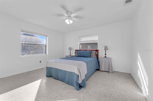 bedroom featuring ceiling fan, light speckled floor, visible vents, and baseboards