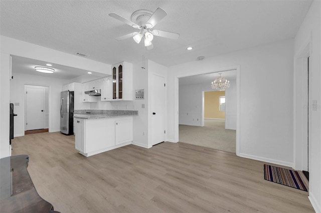 kitchen with white cabinetry, open floor plan, light countertops, freestanding refrigerator, and glass insert cabinets