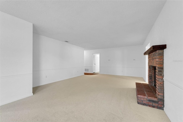 unfurnished living room with carpet floors, a brick fireplace, visible vents, and a textured ceiling