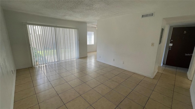 unfurnished room featuring light tile patterned flooring and a textured ceiling