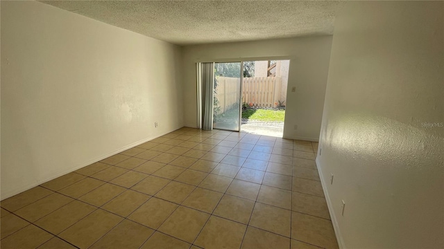 empty room with a textured ceiling and light tile patterned floors