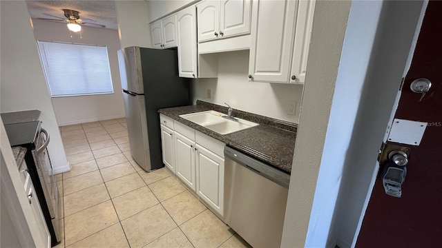 kitchen featuring light tile patterned flooring, appliances with stainless steel finishes, white cabinetry, sink, and ceiling fan