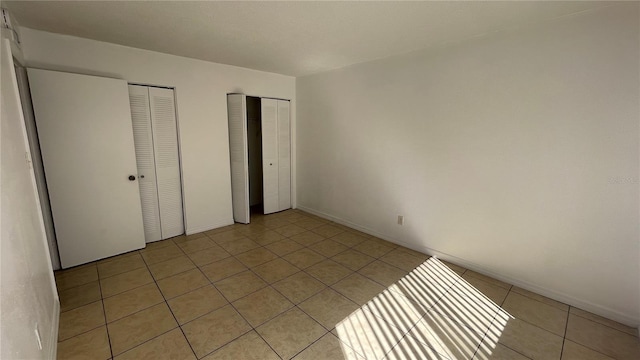 unfurnished bedroom with multiple closets and light tile patterned floors