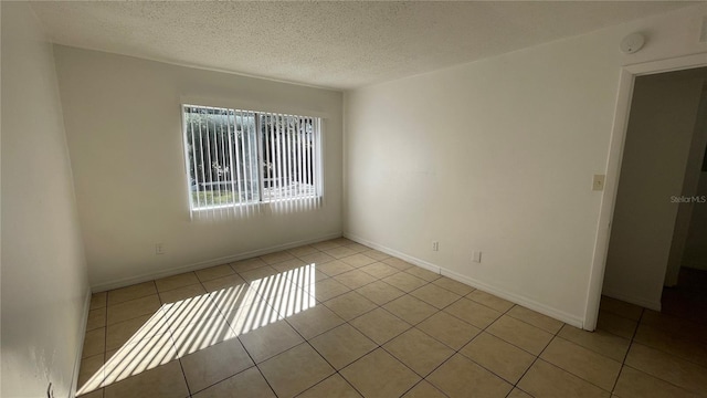 tiled empty room featuring a textured ceiling