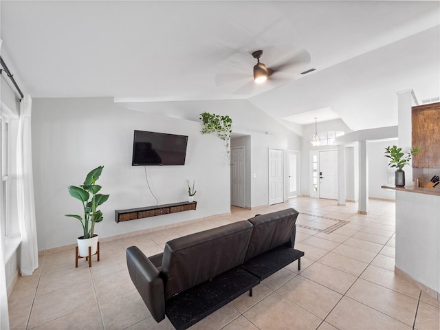 tiled living room featuring lofted ceiling and ceiling fan with notable chandelier