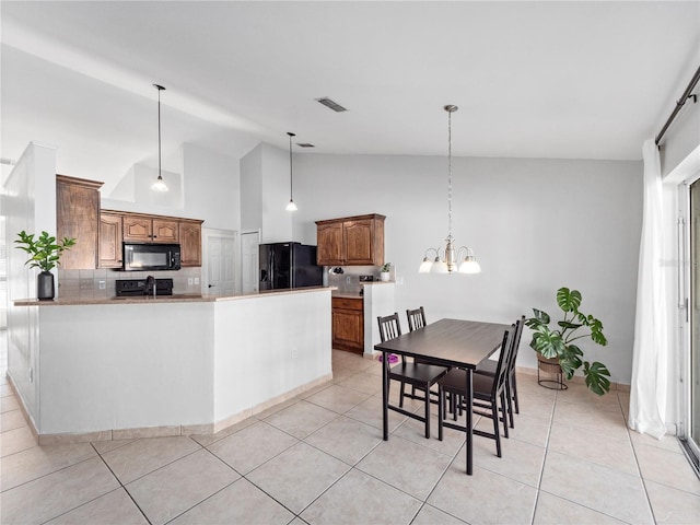 kitchen featuring backsplash, decorative light fixtures, light tile patterned floors, and black appliances