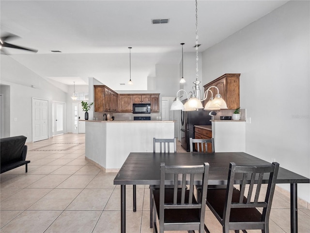 tiled dining area featuring ceiling fan with notable chandelier and high vaulted ceiling