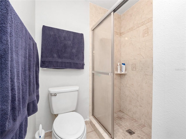 bathroom with a shower with shower door and toilet