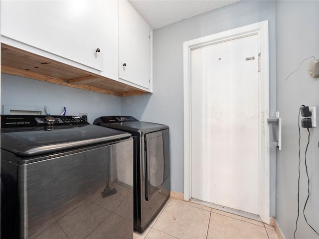 clothes washing area featuring independent washer and dryer, light tile patterned floors, cabinets, and a textured ceiling