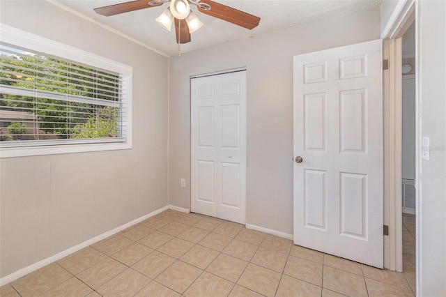 unfurnished bedroom featuring ceiling fan, a closet, and light tile patterned floors