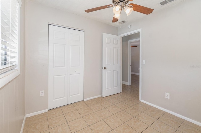 unfurnished bedroom featuring light tile patterned flooring, ceiling fan, and a closet