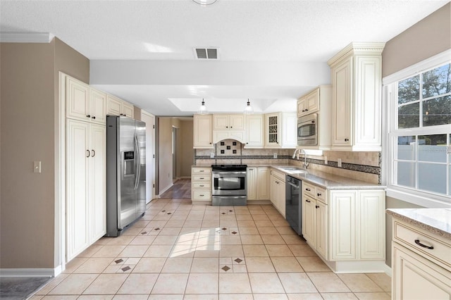 kitchen with light tile patterned flooring, sink, stainless steel appliances, cream cabinets, and decorative backsplash