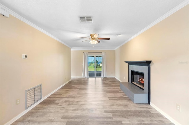 unfurnished living room featuring ceiling fan, ornamental molding, a tile fireplace, and light wood-type flooring