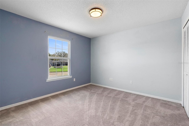 carpeted empty room with a textured ceiling