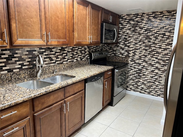 kitchen featuring appliances with stainless steel finishes, tasteful backsplash, sink, light tile patterned floors, and light stone counters