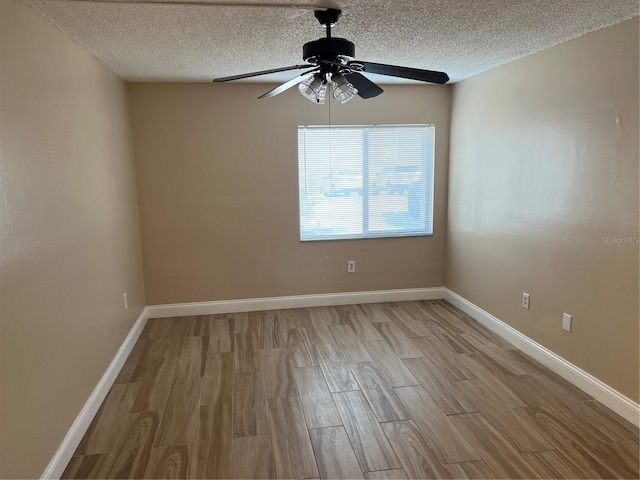 empty room with ceiling fan, a textured ceiling, and light wood-type flooring