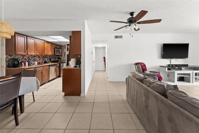 5201 Vineland Rd Unit 112, Orlando, FL 32811 - kitchen featuring open floor plan, visible vents, ceiling fan, brown cabinetry, and appliances with stainless steel finishes