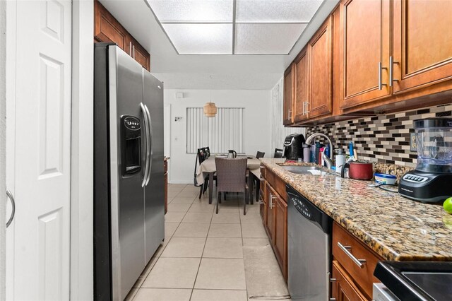 5201 Vineland Rd Unit 112, Orlando, FL 32811 - kitchen with brown cabinetry, a sink, light tile patterned flooring, tasteful backsplash, and appliances with stainless steel finishes