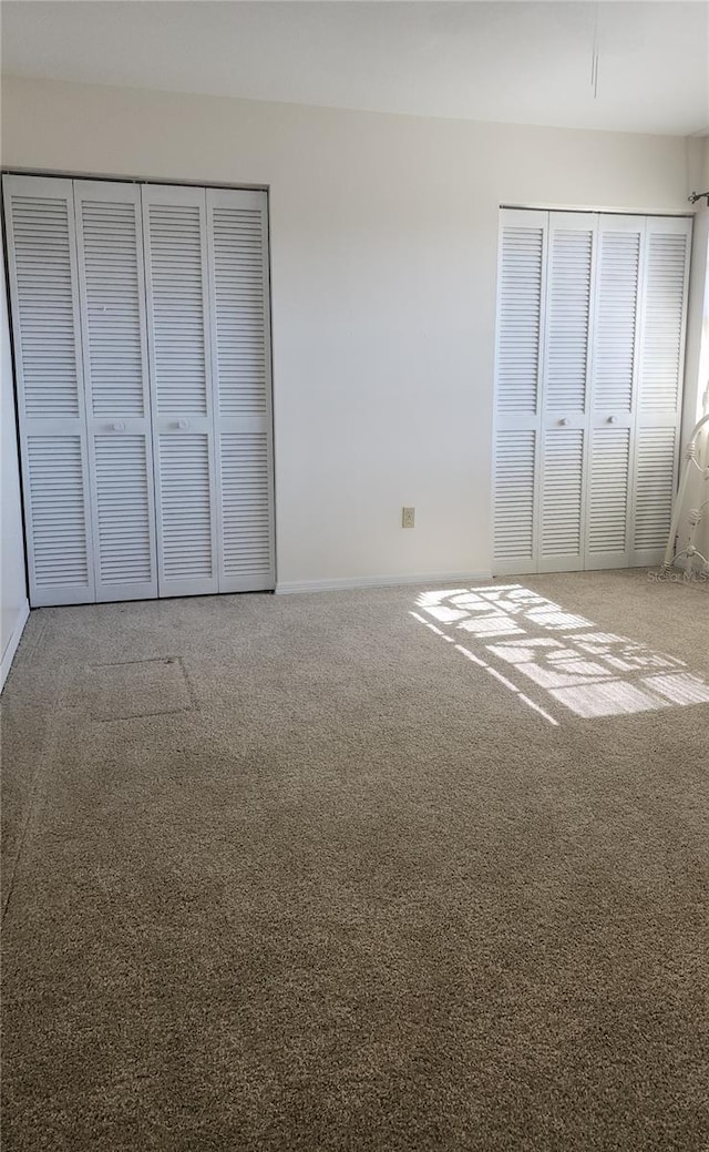 unfurnished bedroom with carpet flooring and two closets