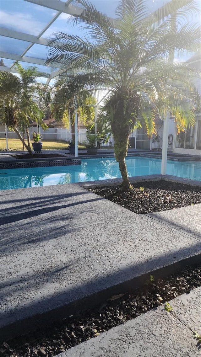 view of swimming pool featuring glass enclosure