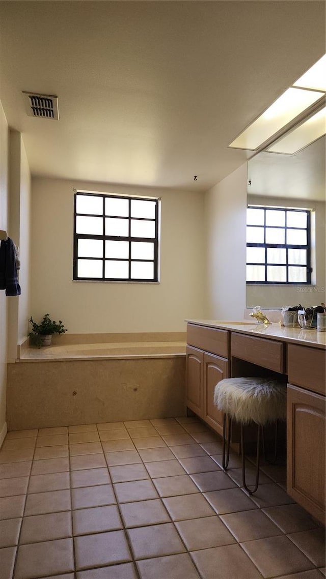 bathroom with a bath, vanity, and tile patterned floors