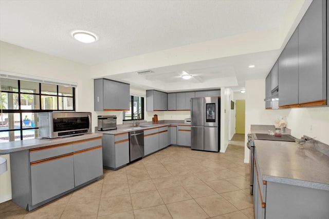 11419 Donneymoor Dr, Riverview, FL 33569 - kitchen with appliances with stainless steel finishes, gray cabinets, a raised ceiling, under cabinet range hood, and ceiling fan